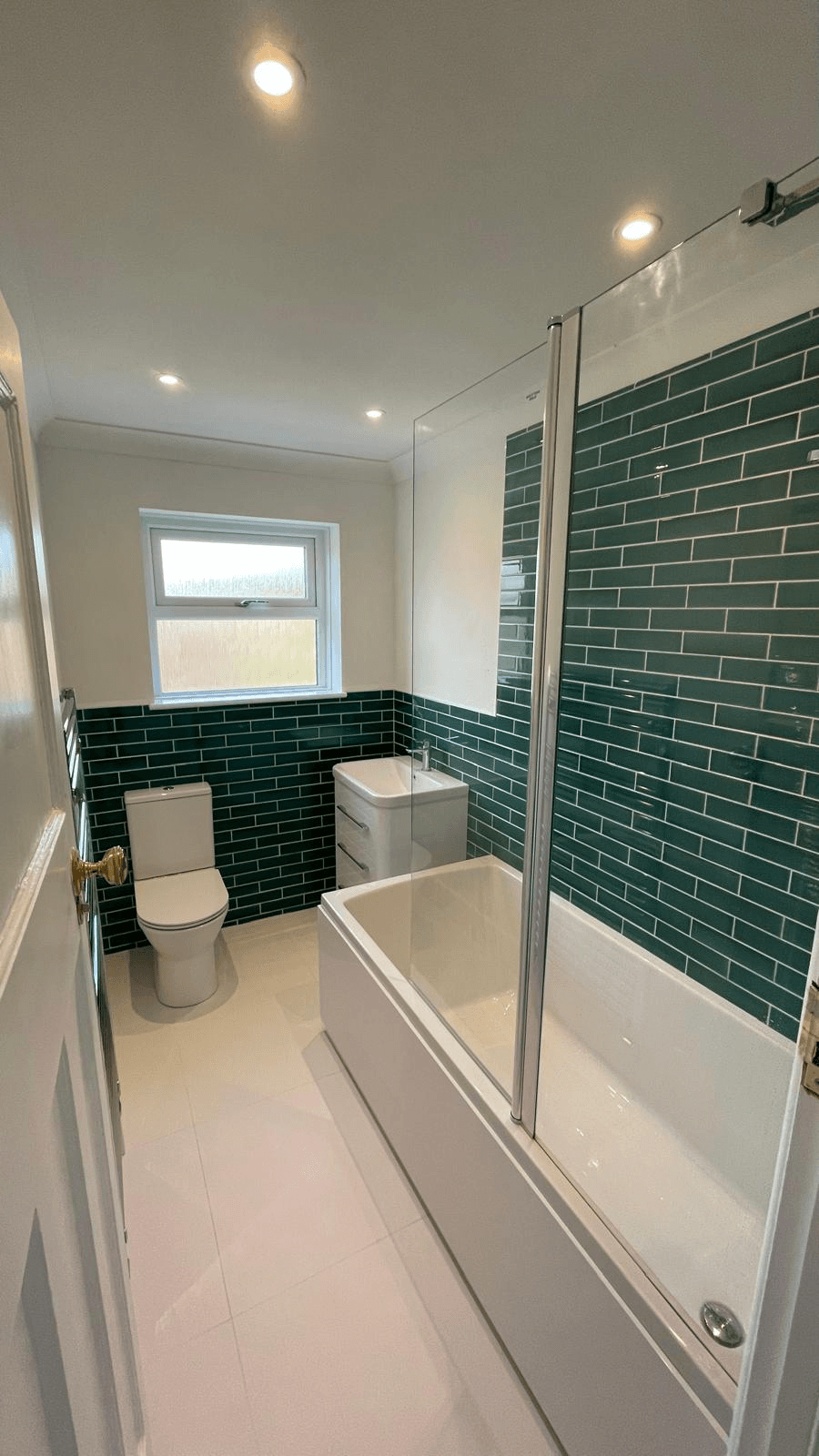 Completed bathroom — green metro tiled walls with bath and shower screen