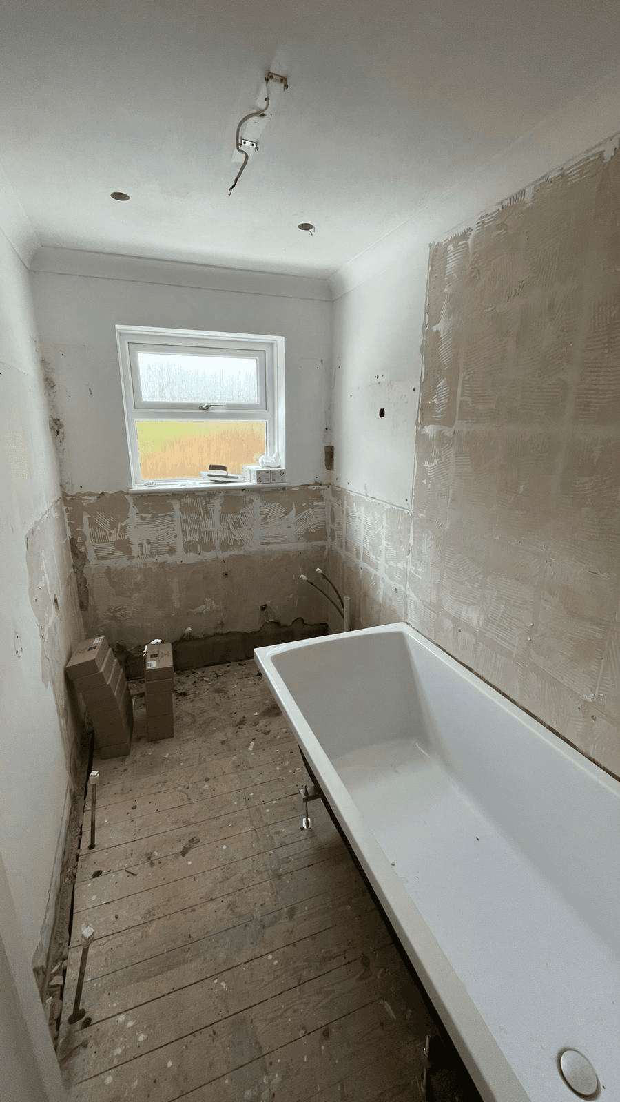 Bathroom refurbishment in progress — bath installed, walls ready for tiling