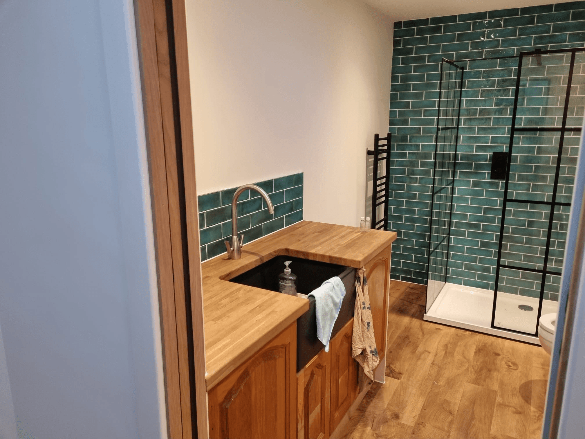 Completed bathroom — teal metro tiles, oak vanity unit and walk-in shower