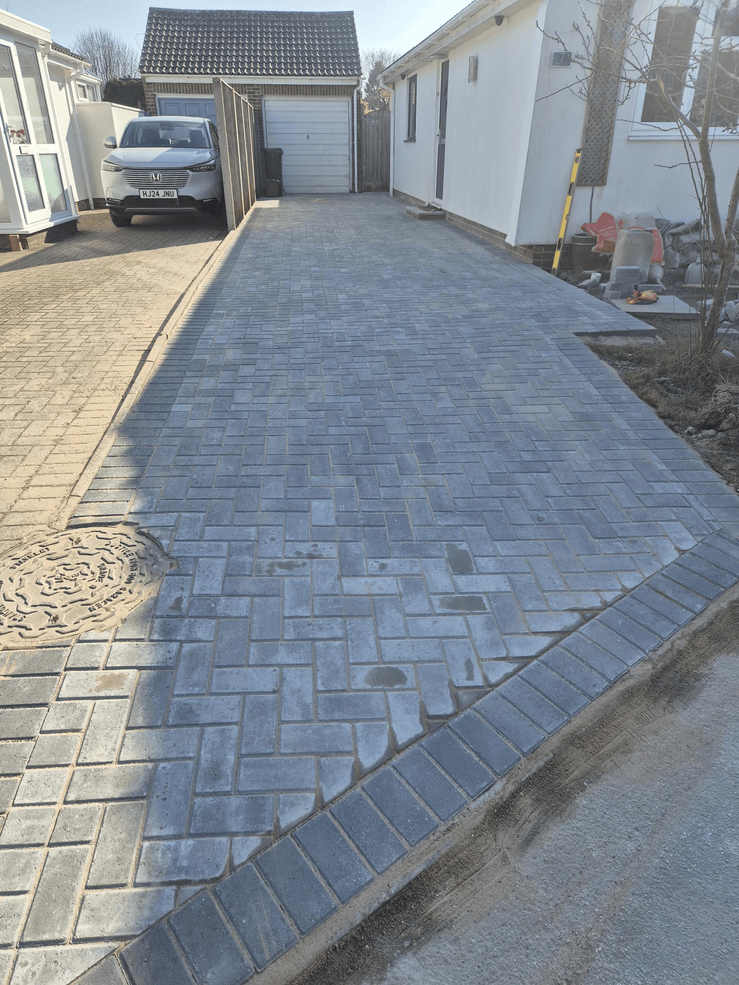 Completed block paved driveway — grey herringbone pattern with brick edging