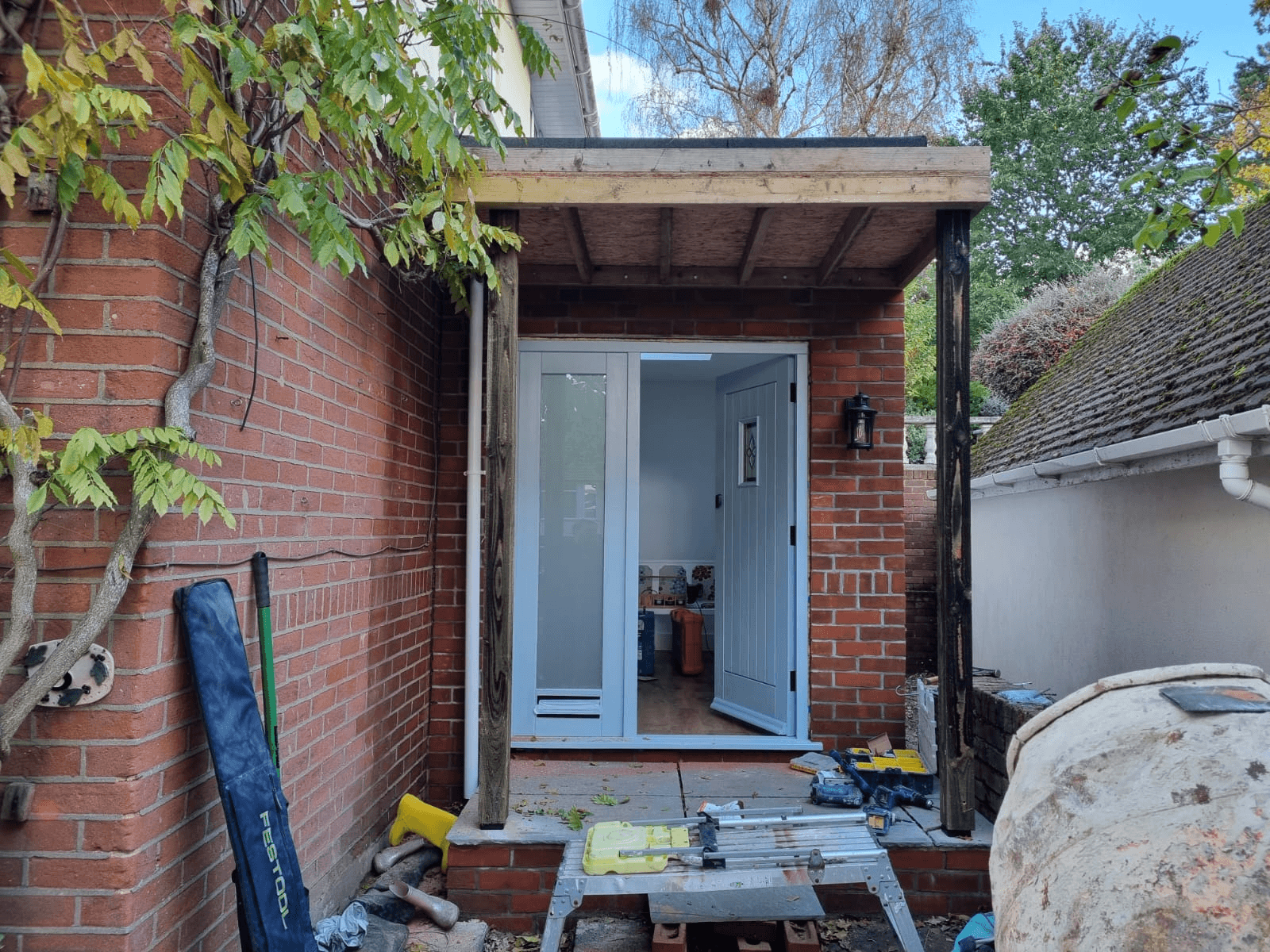 Brick side extension under construction — new door and roof fitted