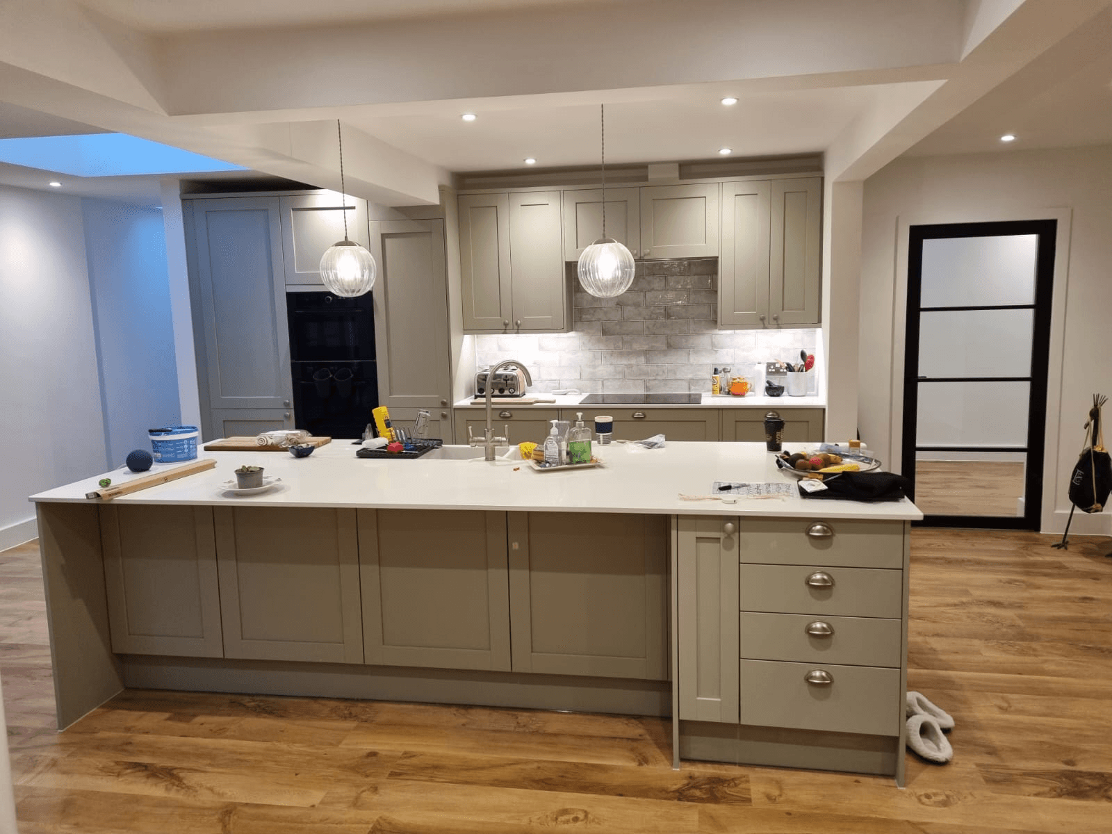 Completed grey shaker kitchen with large island and stone tile splashback