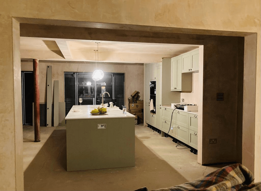 Kitchen island being fitted during renovation — open-plan layout through new knock-through