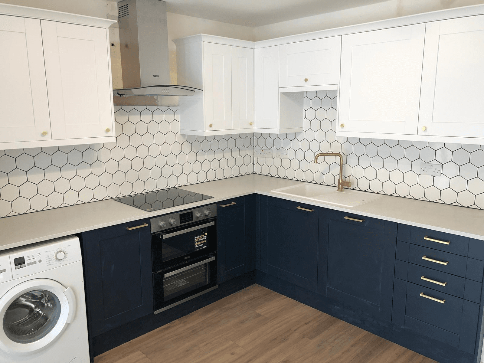 Completed kitchen renovation — navy and white shaker units with hexagon tile splashback