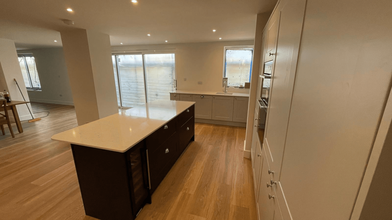 Completed open-plan kitchen — island unit, white cabinets and wood flooring