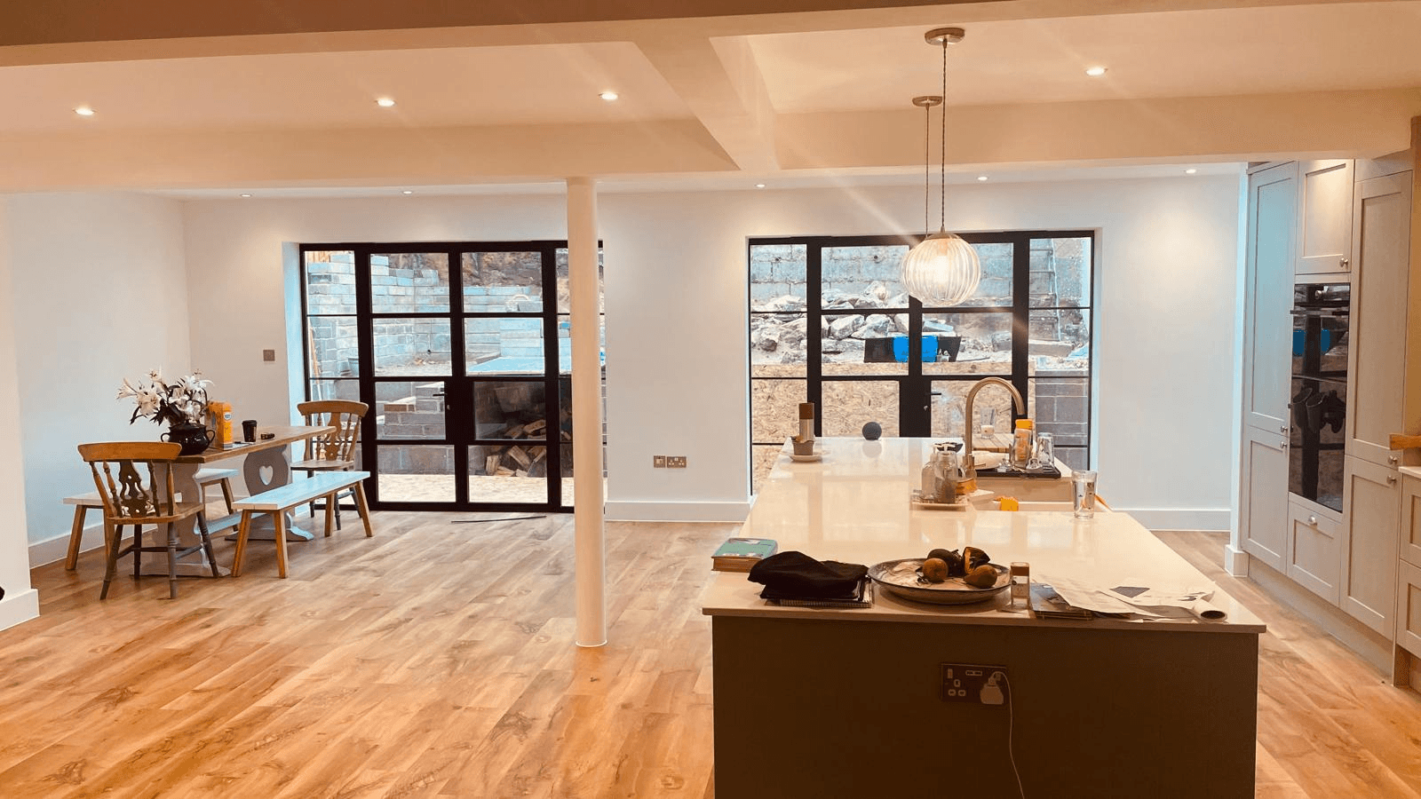 Completed open-plan kitchen with island, wood flooring and Crittall-style doors