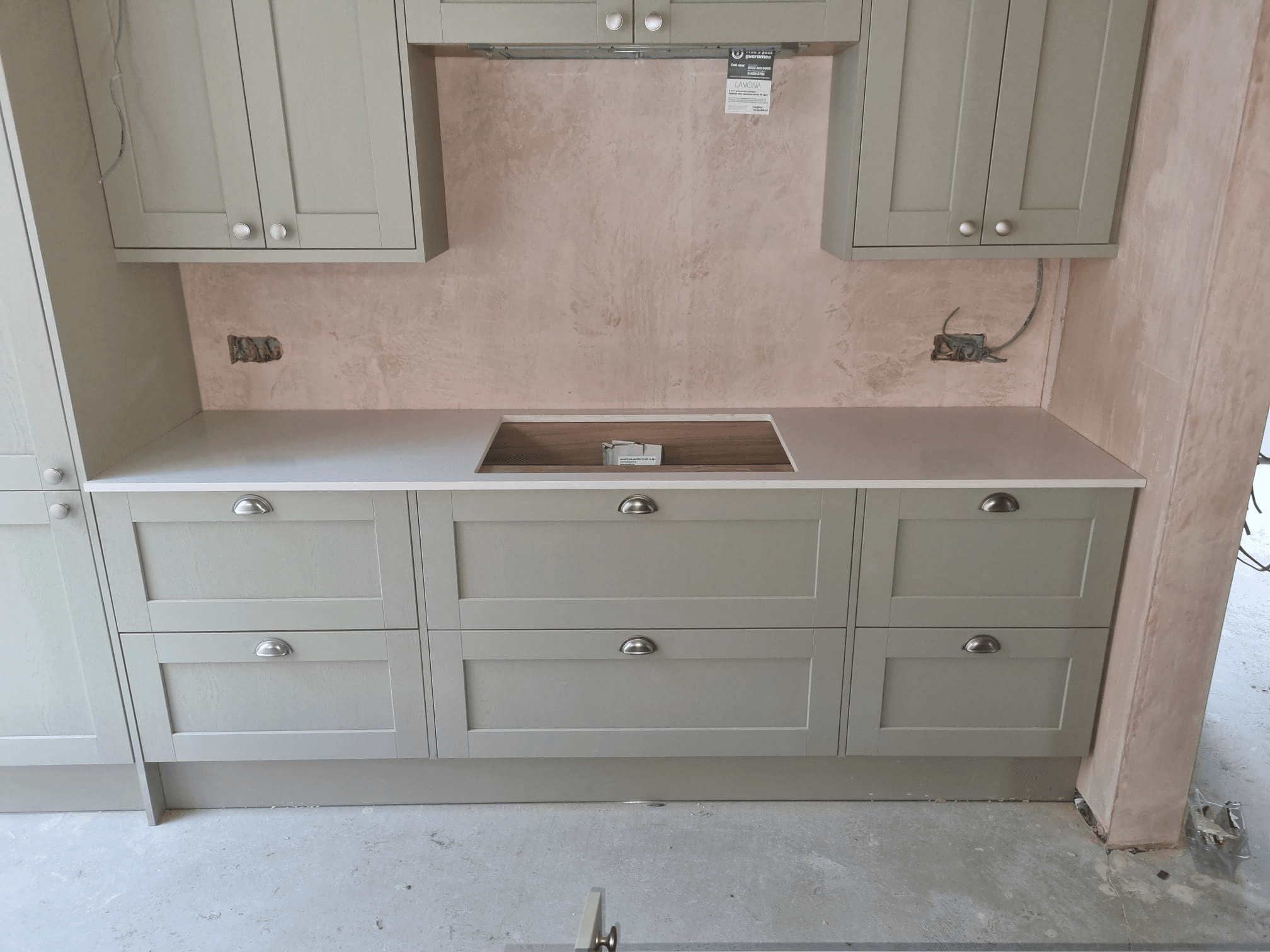 Sage green shaker kitchen units with white quartz worktop — fitting in progress